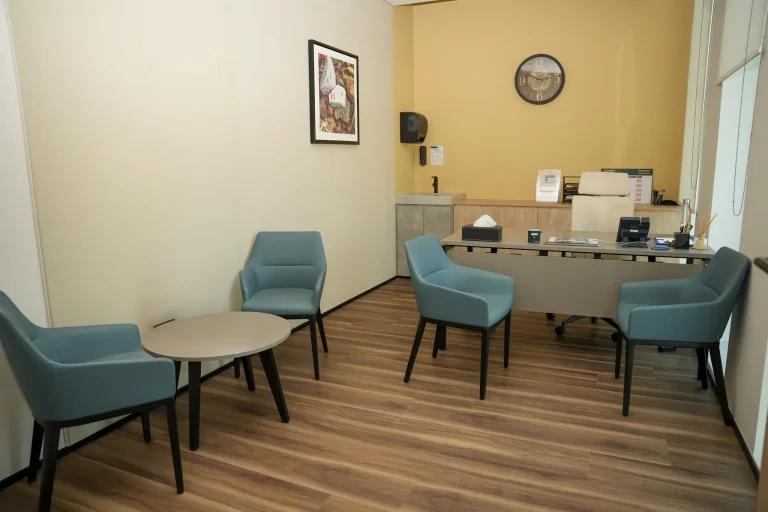 Consultation room at the alkalma Al Bateen clinic with blue armchairs arranged around a low table