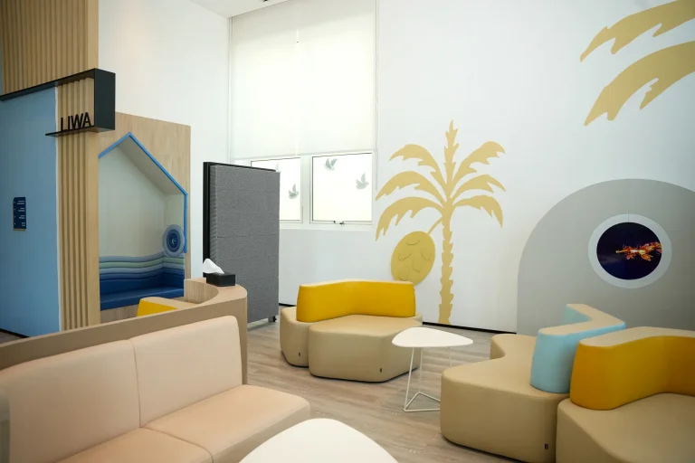 Children's sensory play area at the alkalma Al Bateen clinic with a palm tree mural and modular yellow seating