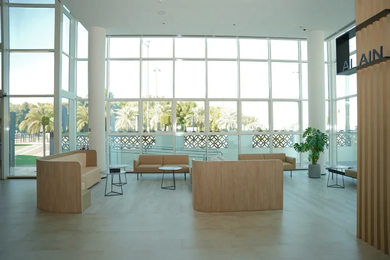 Double-height waiting lounge at the alkalma Al Bateen clinic with floor-to-ceiling windows overlooking palm trees