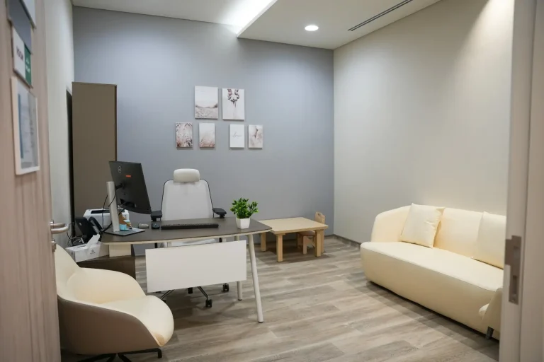 Consultation room at the alkalma Al Falah clinic with a desk, an examination chair and a sofa