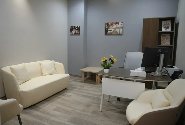 Consultation office at the alkalma Al Falah clinic with a cream sofa and a clinician's desk