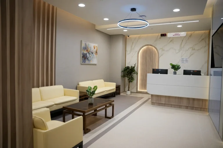 Reception desk at the alkalma Al Falah clinic with a ring pendant light and an arched wall niche