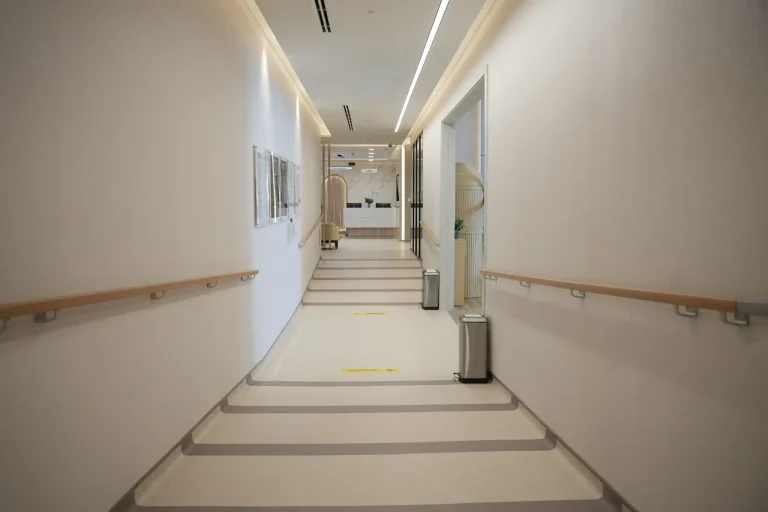 Corridor at the alkalma Al Falah clinic with handrails and framed artwork along the walls
