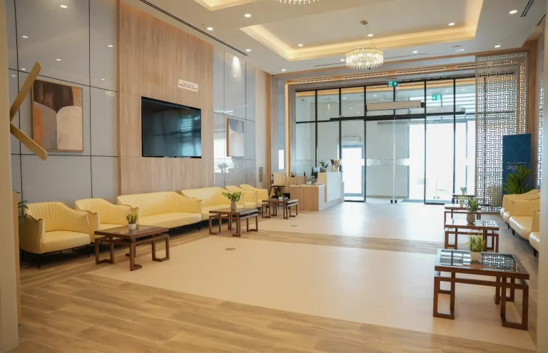 Waiting lounge at the alkalma Al Falah clinic with cream sofas and a wall-mounted screen near the entrance
