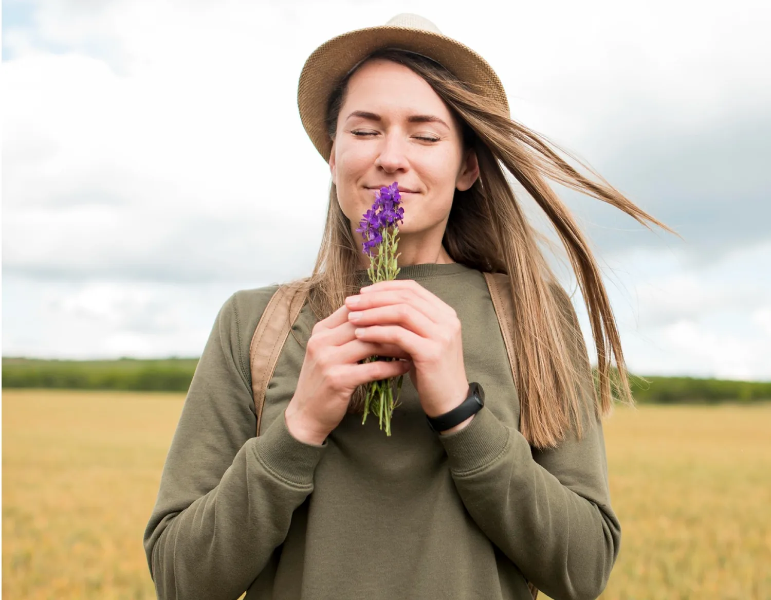 A woman in a field smelling a sprig of lavender