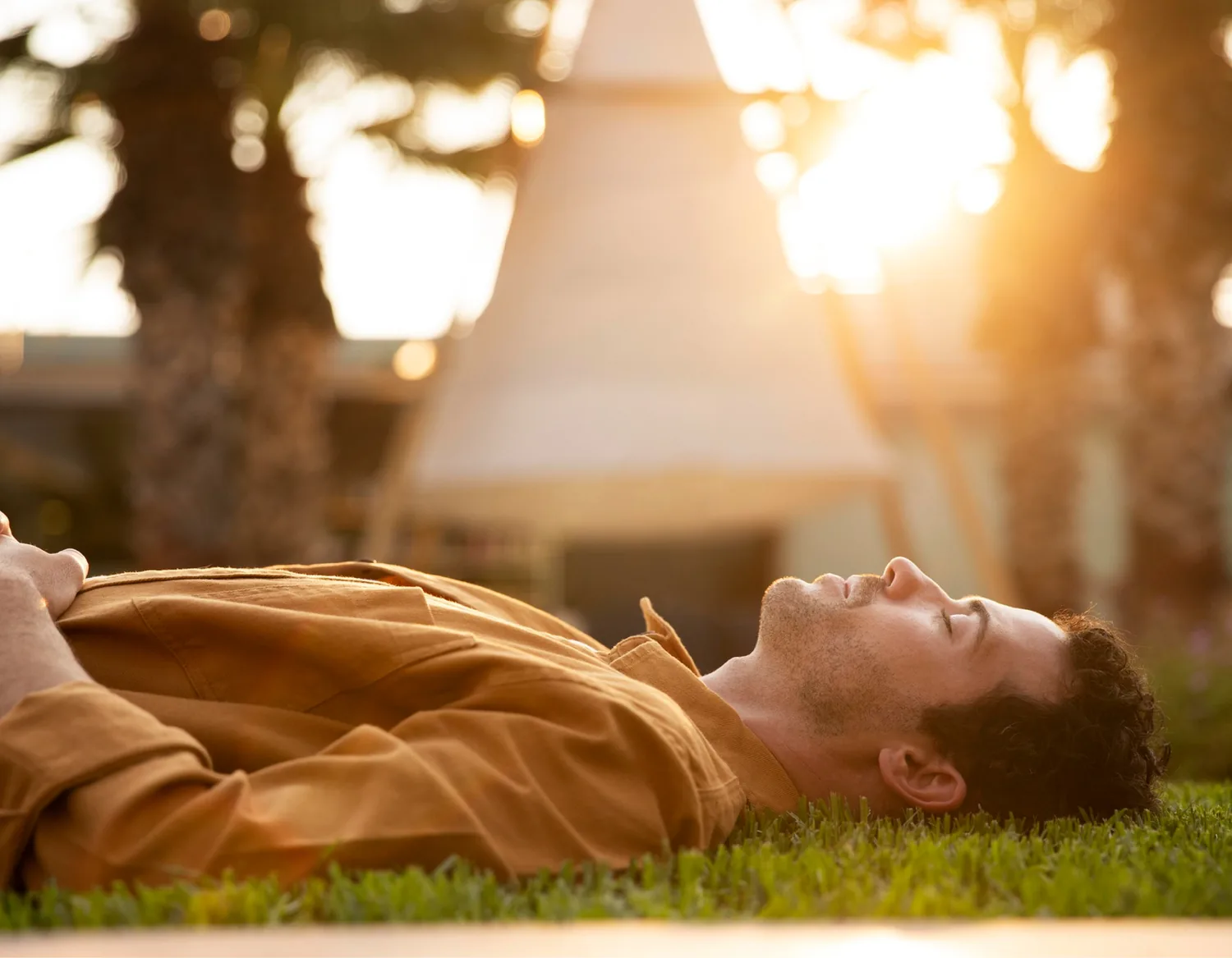 A man lying on the grass with his eyes closed during a body scan