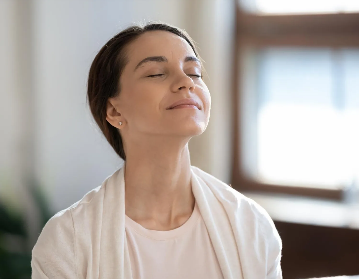 A woman sitting calmly indoors practising box breathing